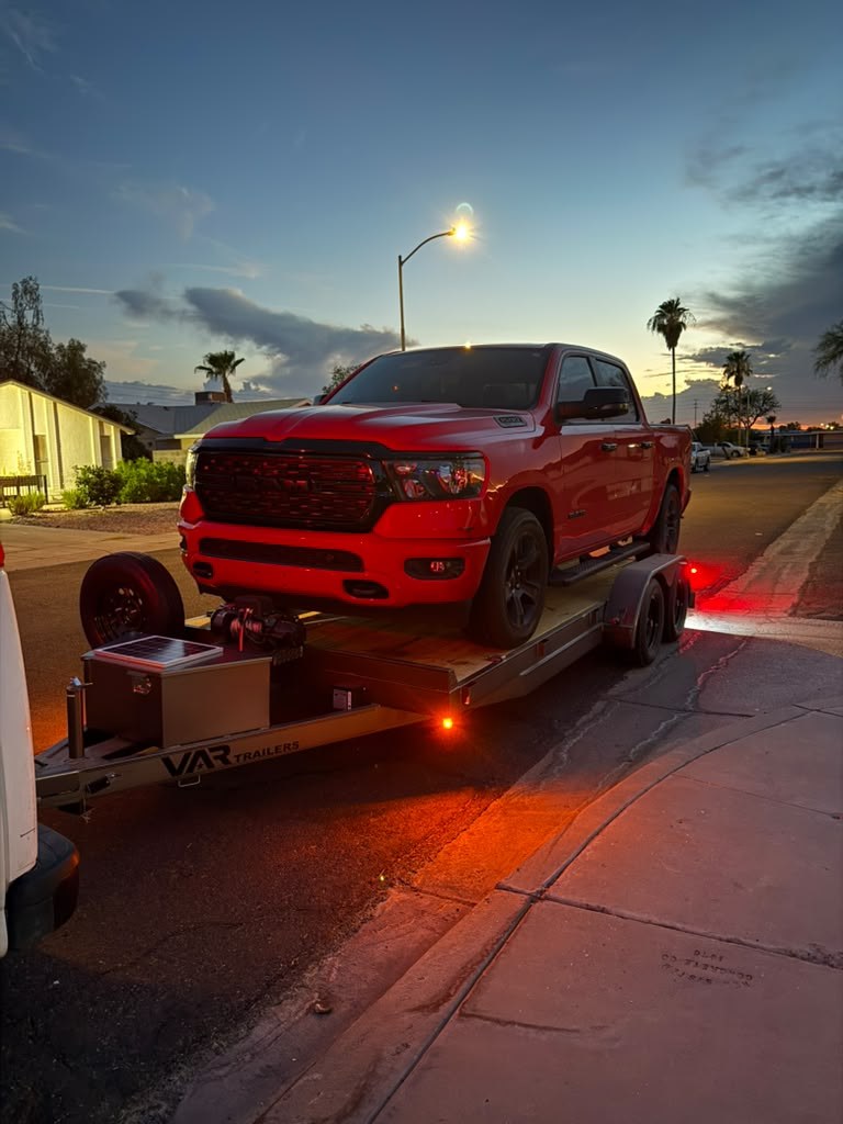 Red pickup truck secured on a trailer at dusk